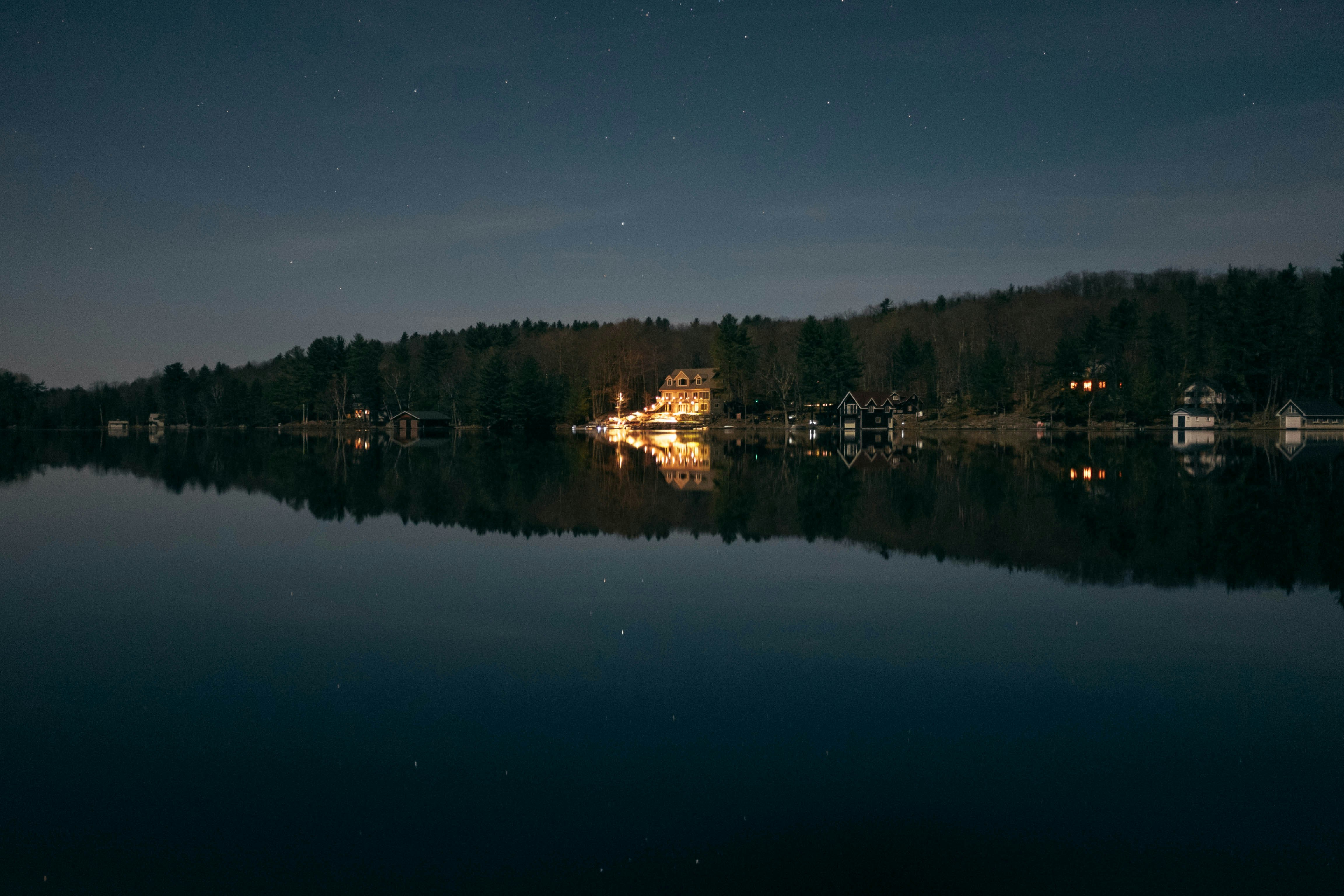 lighted beige house beside shoreline during nighttime